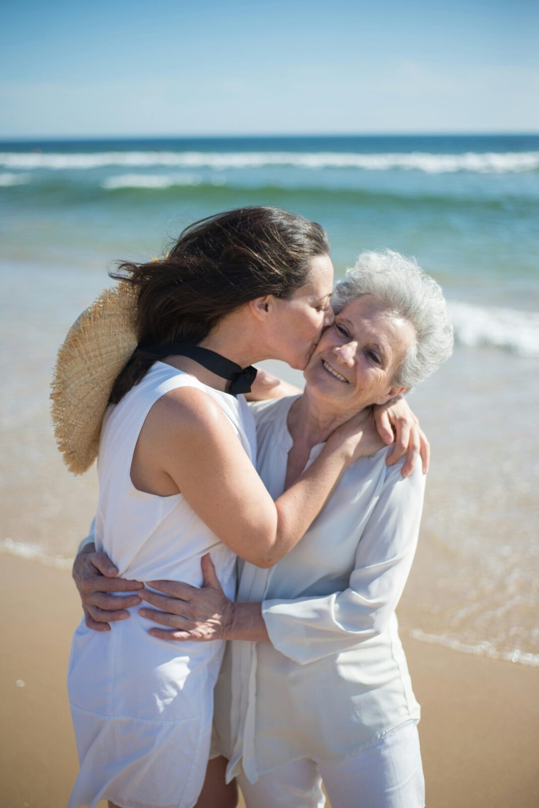 Adult daughter embracing her mother on the beach &mdash; helping a parent with Medicare